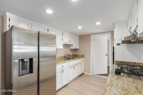 a kitchen with stainless steel appliances granite countertop a refrigerator and a stove