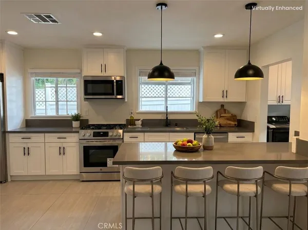 a kitchen with granite countertop a stove a sink a window and chairs