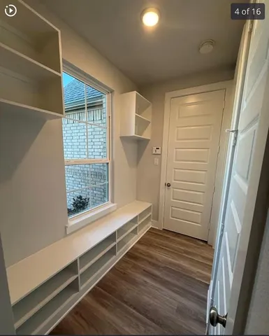 a view of walk in closet with wooden floor and fence