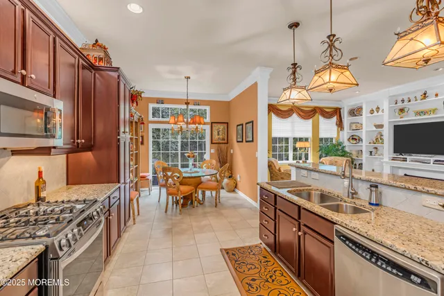 a view of a kitchen with kitchen island granite countertop a sink a counter space cabinets and stainless steel appliances