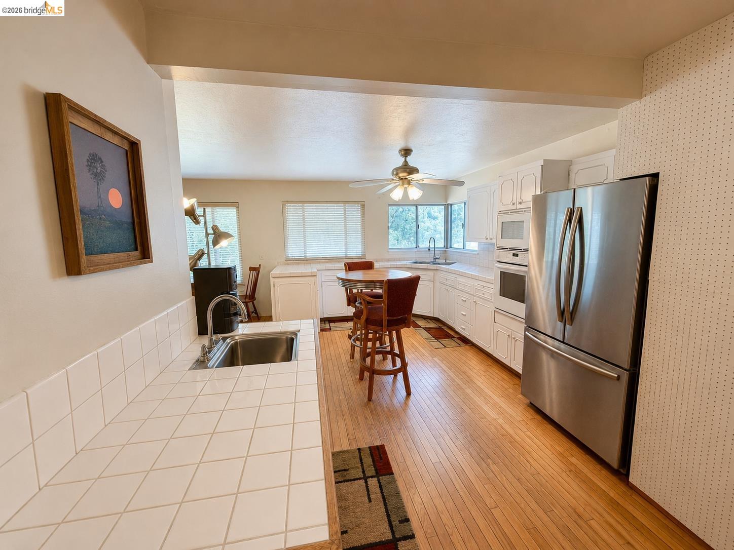 18195 Wards Ferry Road Sonora, CA 95370 - Photo 15 of 67 Kitchen featuring white cabinetry, light wood-finish flooring, a stainless steel refrigerator, and integrated stainless steel wall oven and microwave