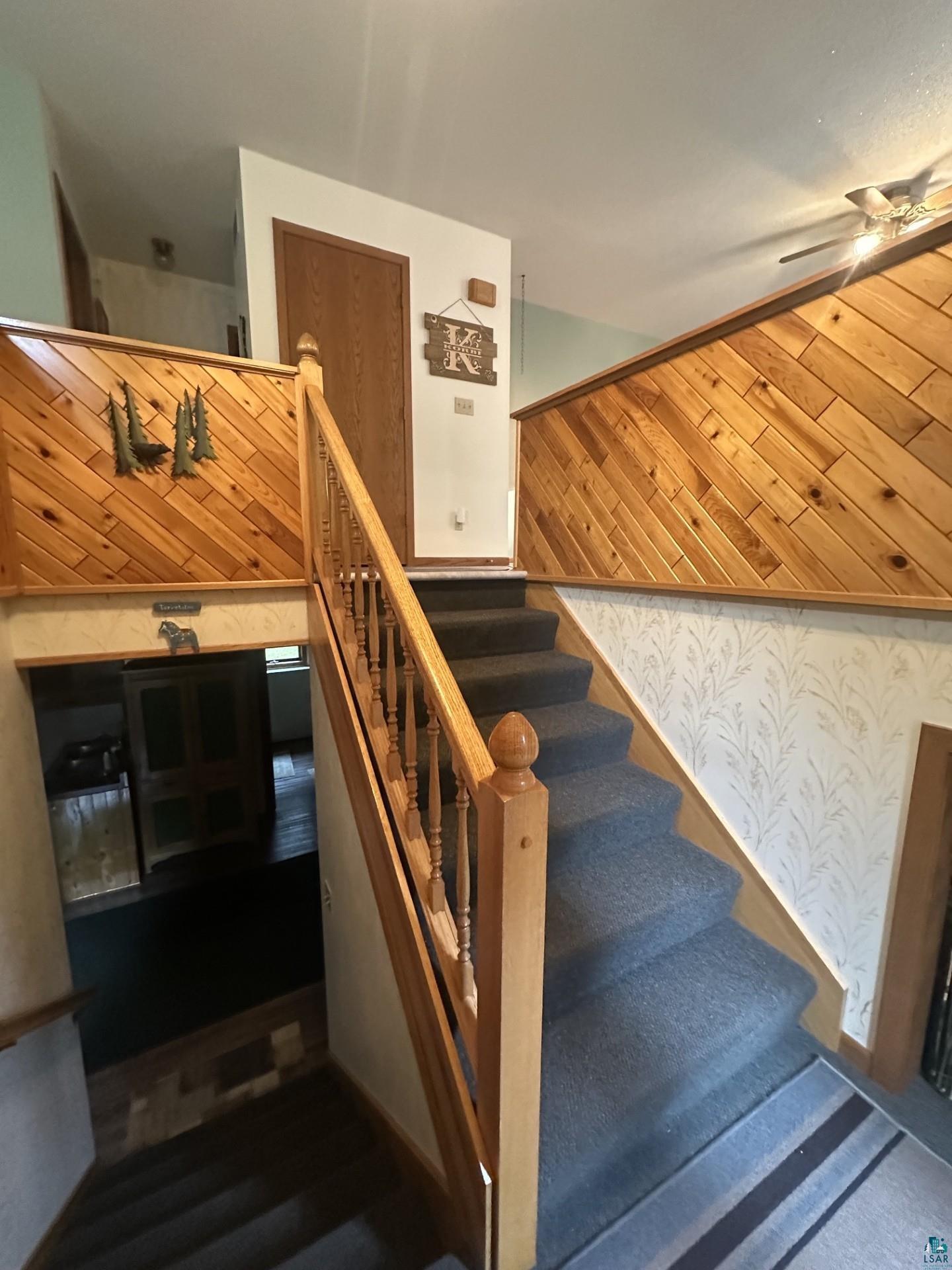 81 Hautaluoma Road Esko, MN 55733 - Photo 21 of 43 Split-level entry with wood-finish balusters and handrail, carpeted stairs, and diagonal wood-panel accent walls