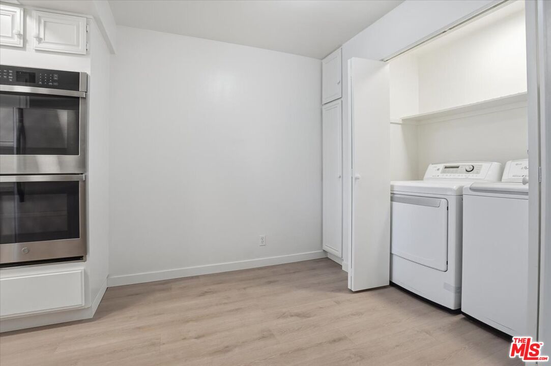15480 Antioch Street, Unit 102 Pacific Palisades, CA 90272 - Photo 7 of 15 a view of a kitchen with white cabinets and wooden floor