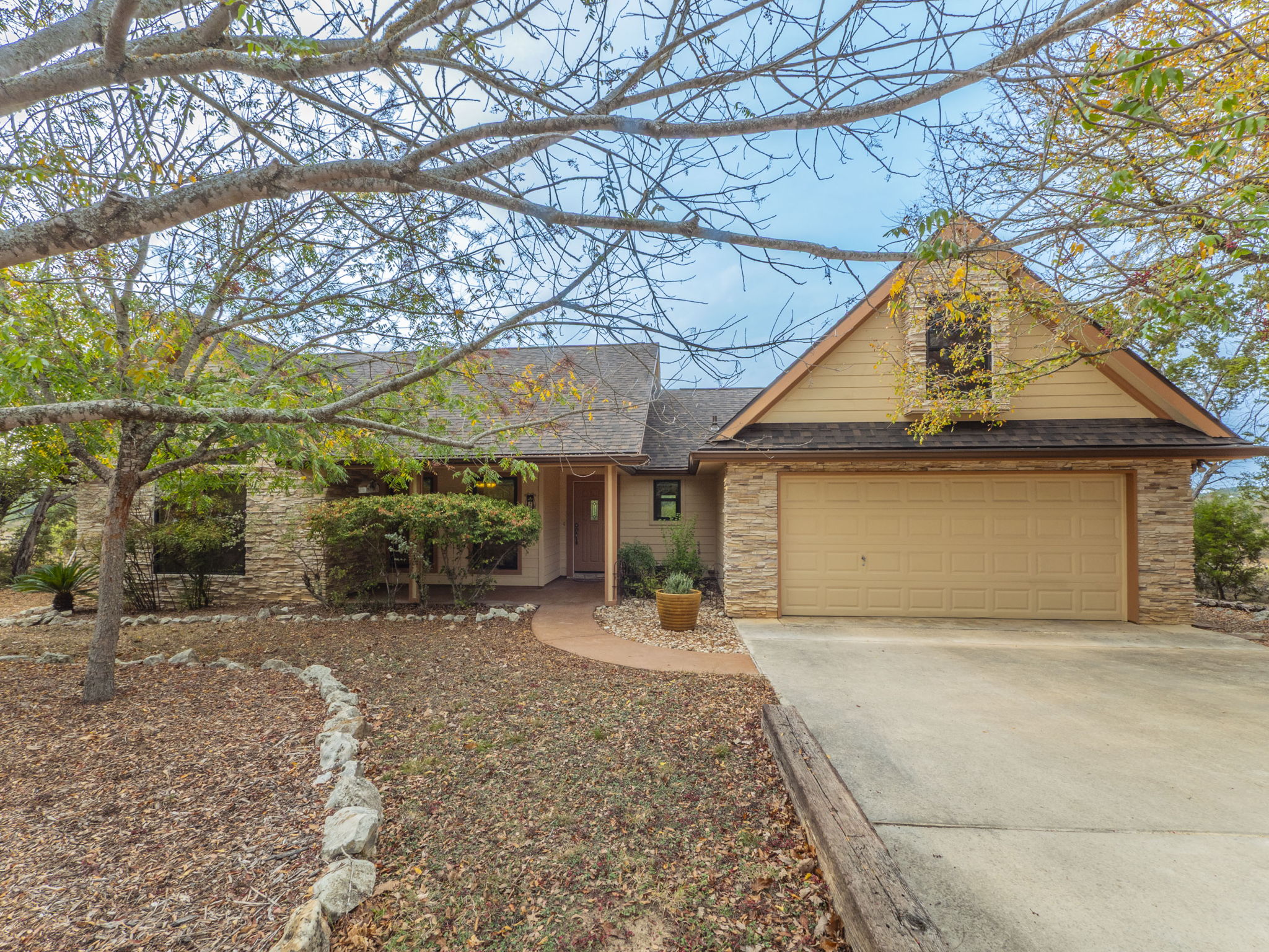 25 Ranch View Trail Wimberley, TX 78676 - Photo 1 of 1 View of front of property with concrete driveway, stone siding, roof with shingles, and a garage