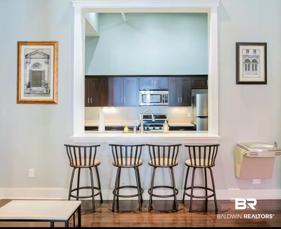 204 Conti Street, Unit 1C Mobile, AL 36602 - Photo 10 of 12 Kitchen featuring a kitchen bar, appliances with stainless steel finishes, light countertops, and dark wood-style floors