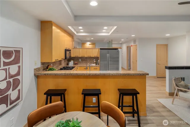 a kitchen with stainless steel appliances kitchen island granite countertop a table chairs in it and wooden floors