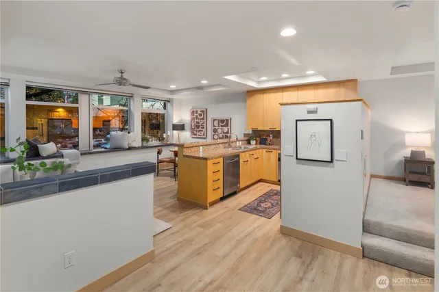 a kitchen with stainless steel appliances granite countertop a refrigerator a sink and a stove with wooden floor