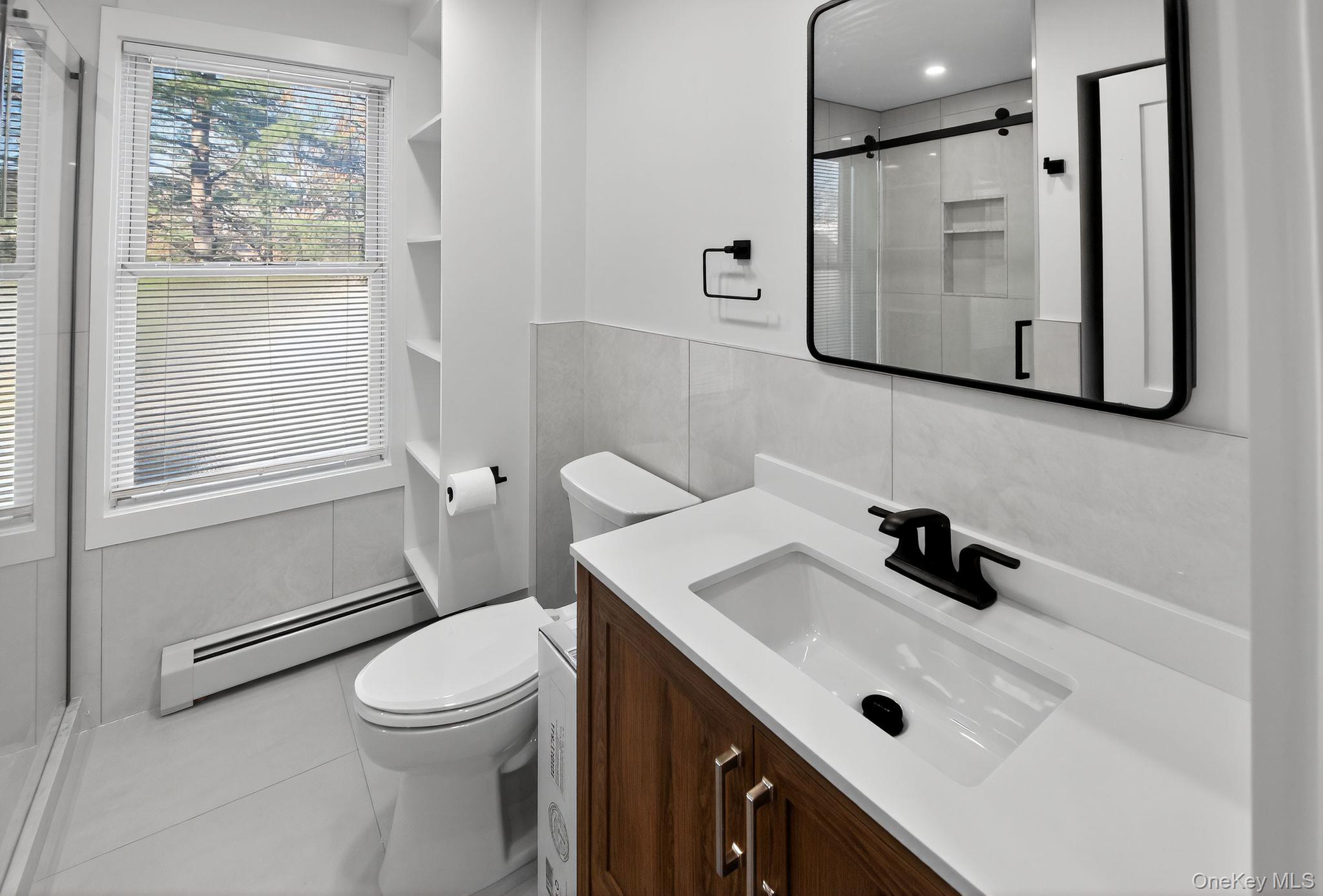153 Franklin Avenue, Unit 2 Pearl River, NY 10965 - Photo 17 of 25 Bathroom featuring a baseboard heating unit, vanity, a shower stall, tile walls, and tile patterned floors