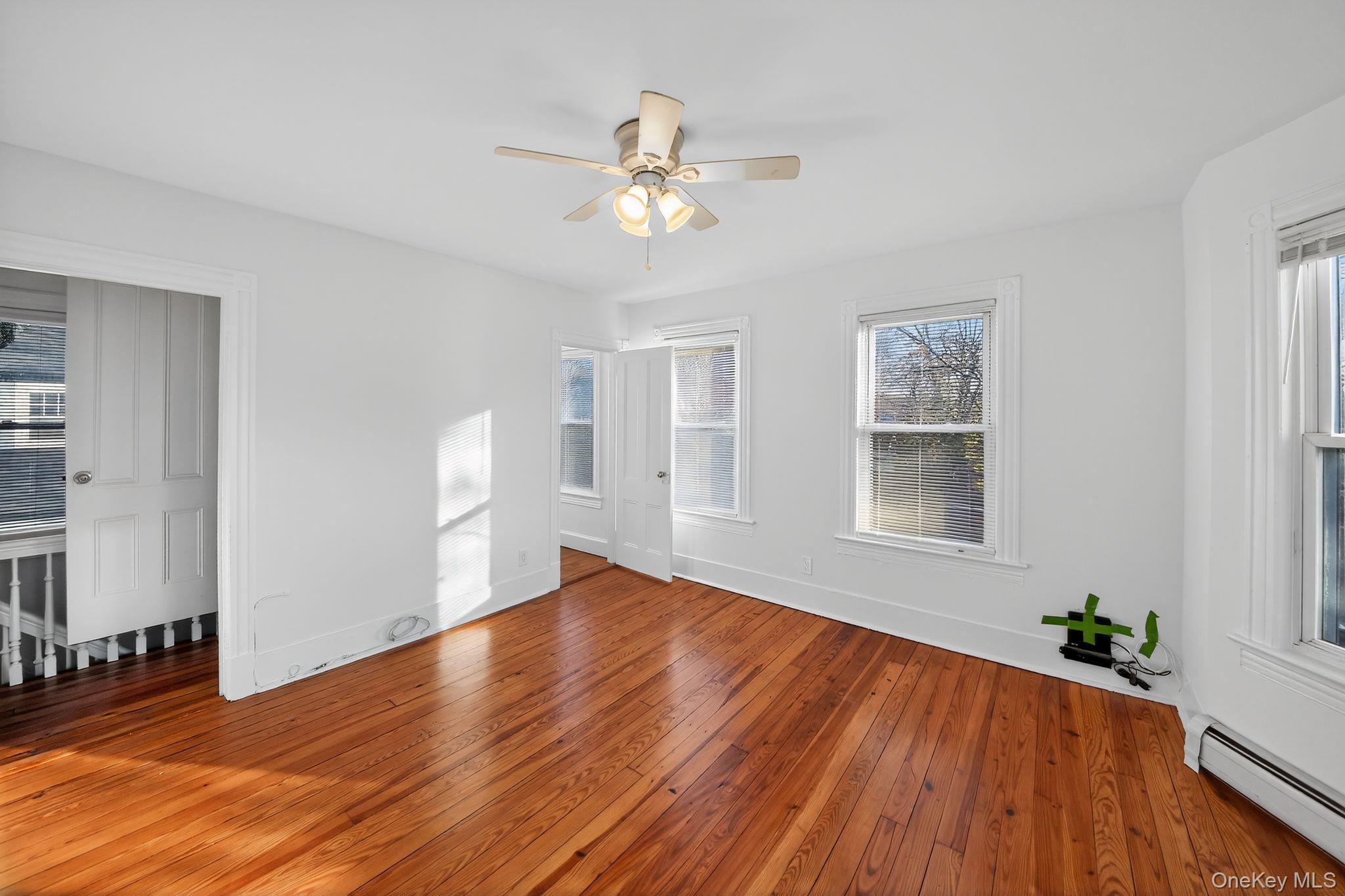 153 Franklin Avenue, Unit 2 Pearl River, NY 10965 - Photo 6 of 25 Unfurnished room featuring baseboard heating, hardwood / wood-style floors, and a ceiling fan