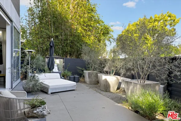 a view of a patio with table and chairs potted plants and large tree