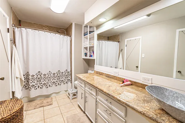a bathroom with a granite countertop sink a mirror a vanity and shower