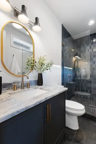 a bathroom with a granite countertop sink a toilet and mirror