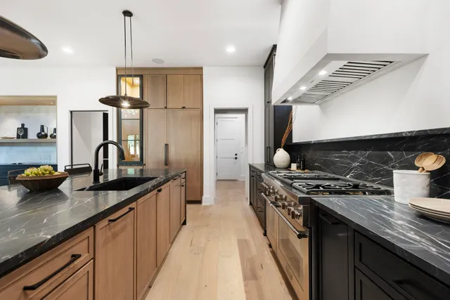 a kitchen with kitchen island granite countertop a sink stainless steel appliances and cabinets
