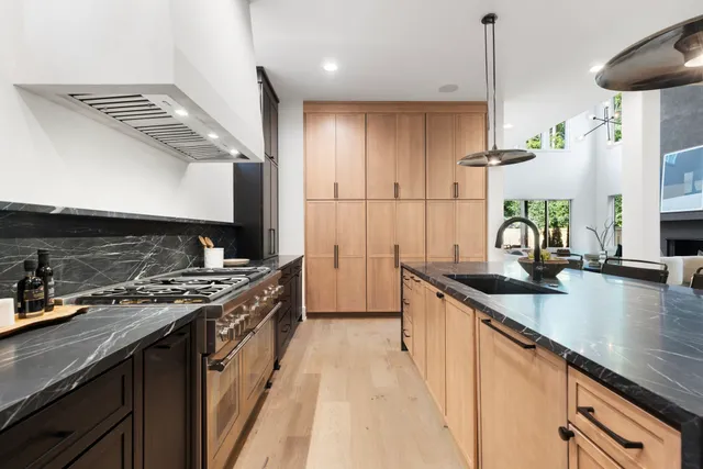 a kitchen with stainless steel appliances granite countertop a sink a stove and a wooden floors