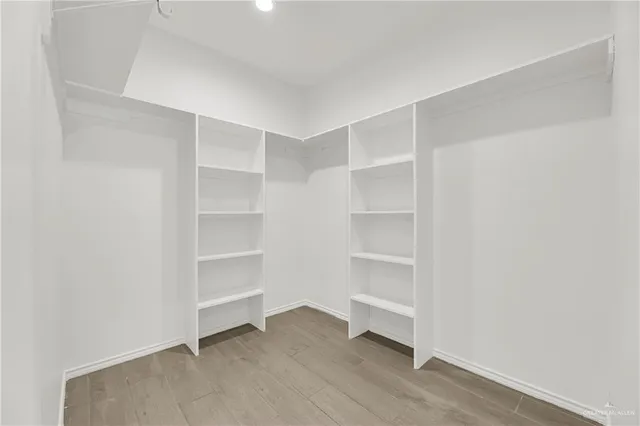 a view of an empty room with wooden floor and windows