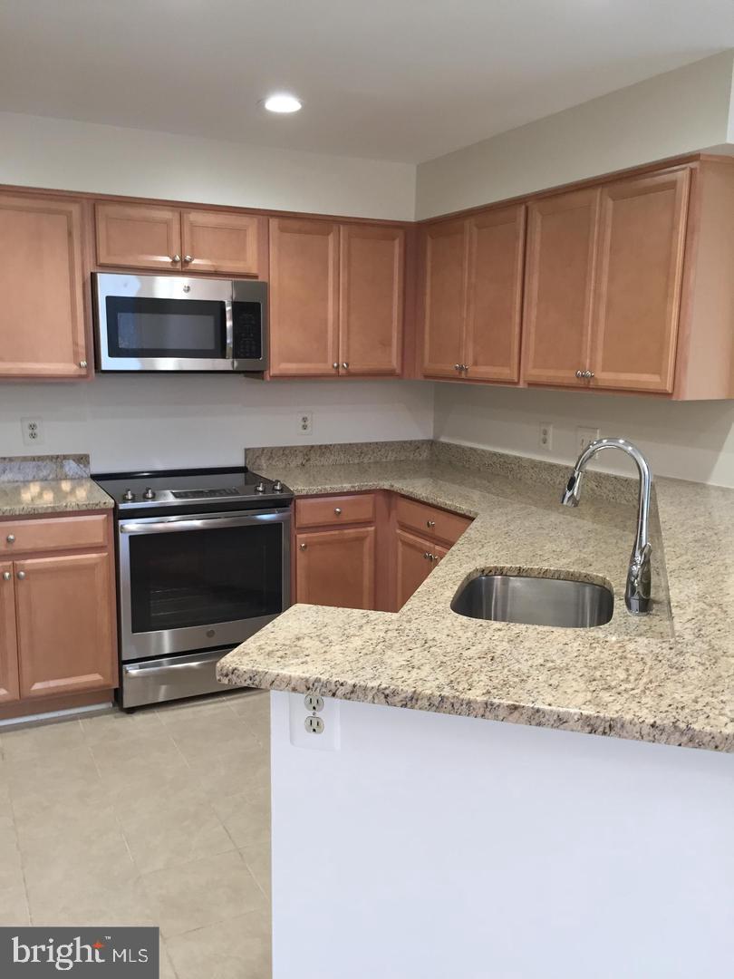 11242 Harbor Court, Unit 1242 Reston, VA 20191 - Photo 4 of 8 a kitchen with stainless steel appliances granite countertop a sink a stove and microwave