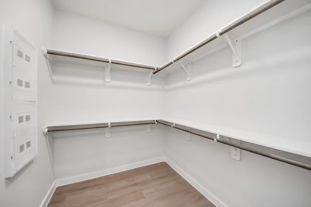 an empty room with wooden floor fan and windows