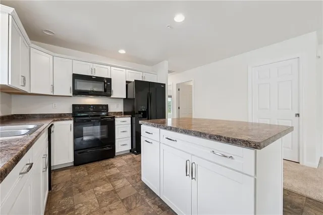 a kitchen with granite countertop white cabinets and stainless steel appliances