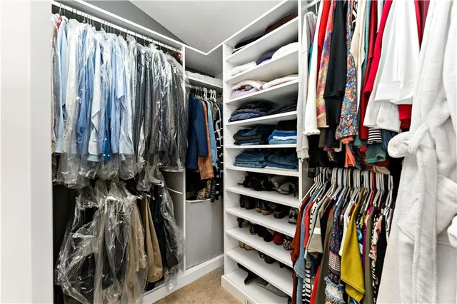 a view of walk in closet with clothes and shoes