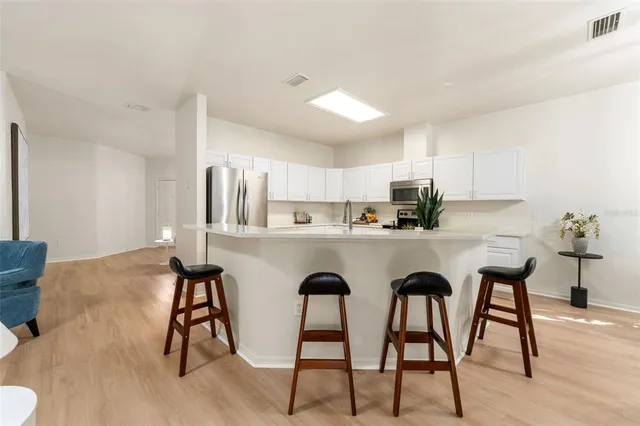 a kitchen with stainless steel appliances a dining table chairs and sink