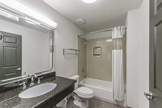 a en suite bathroom with a granite countertop sink and a mirror