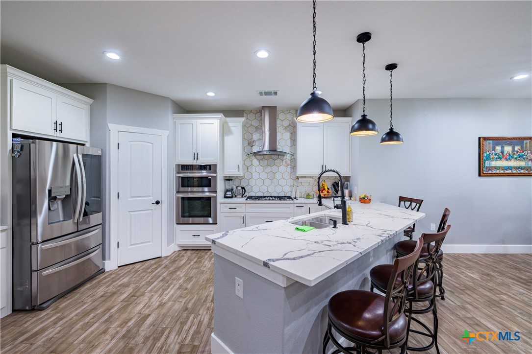 200 Wood Cove Georgetown, TX 78633 - Photo 14 of 22 a kitchen with granite countertop kitchen island stainless steel appliances a stove a sink a refrigerator cabinets and wooden floor