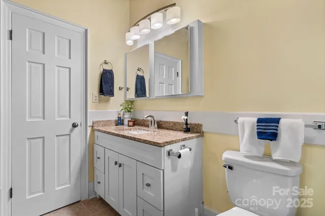a bathroom with a granite countertop sink a mirror and a toilet