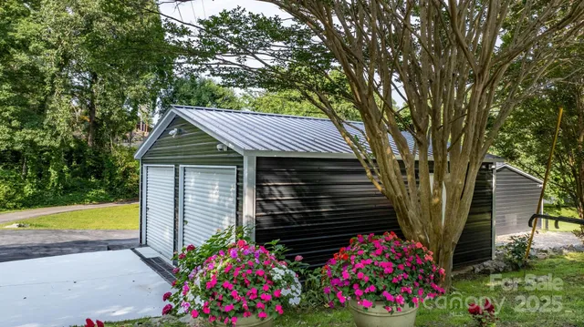 a view of a house with large trees and flower plants