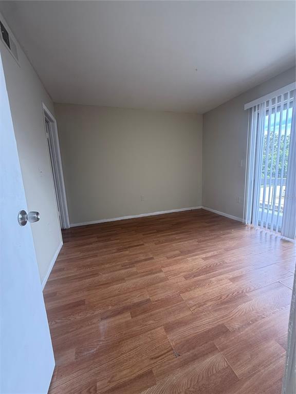 1019 West Sumner Street Kissimmee, FL 34741 - Photo 7 of 12 a view of an empty room with wooden floor and a window