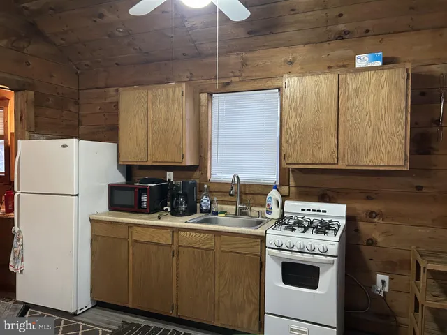 a kitchen with a sink a stove cabinets and white appliances