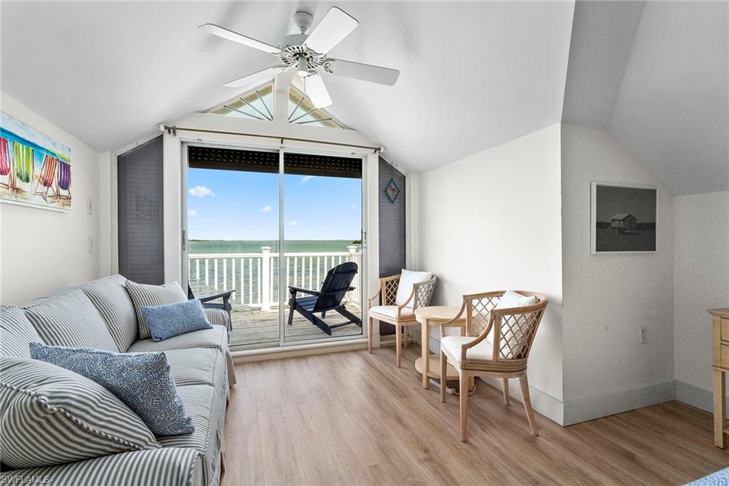 143 Useppa Island Bokeelia, FL 33922 - Photo 13 of 22 Living area with a water view, vaulted ceiling, light wood-style floors, and ceiling fan