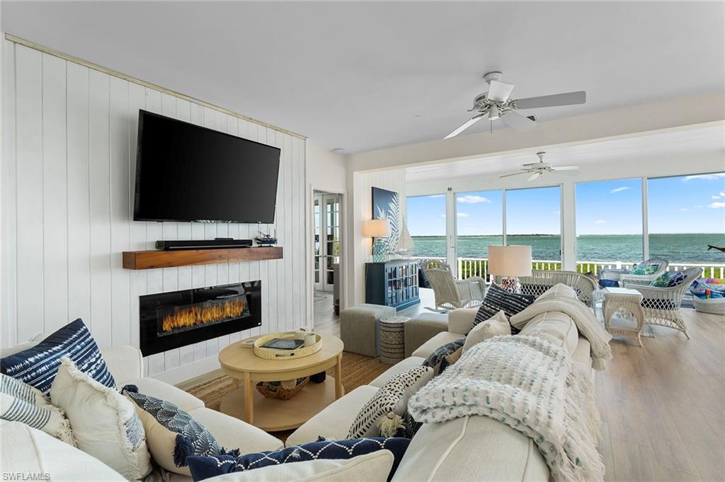 143 Useppa Island Bokeelia, FL 33922 - Photo 6 of 22 Living area featuring wood finished floors, a glass covered fireplace, and a ceiling fan