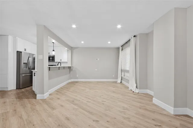 a view of a kitchen with refrigerator and wooden floor