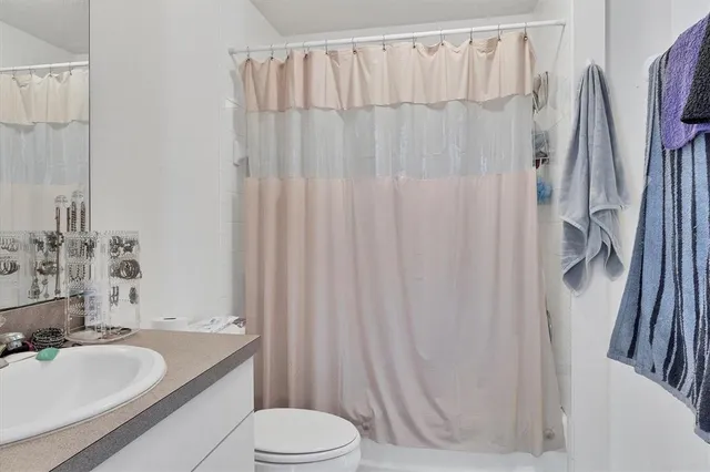 a bathroom with a granite countertop sink toilet and a mirror