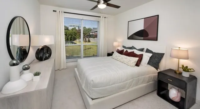 a bedroom with a bed a mirror and a window