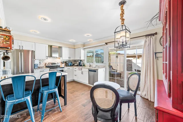 a dining room with stainless steel appliances kitchen island granite countertop furniture and a chandelier