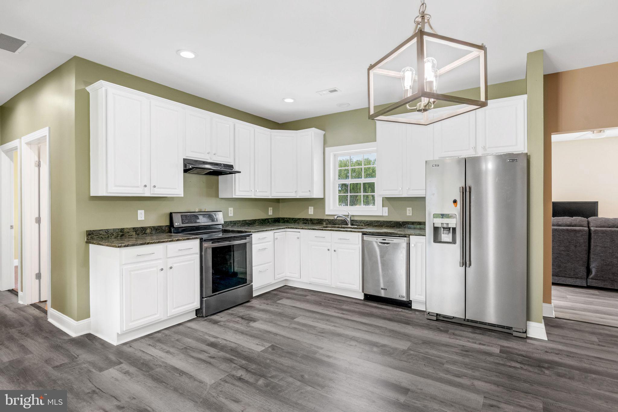 27407 Walking Run Milton, DE 19968 - Photo 10 of 25 a kitchen with kitchen island granite countertop a refrigerator a sink dishwasher a stove and white cabinets with wooden floor