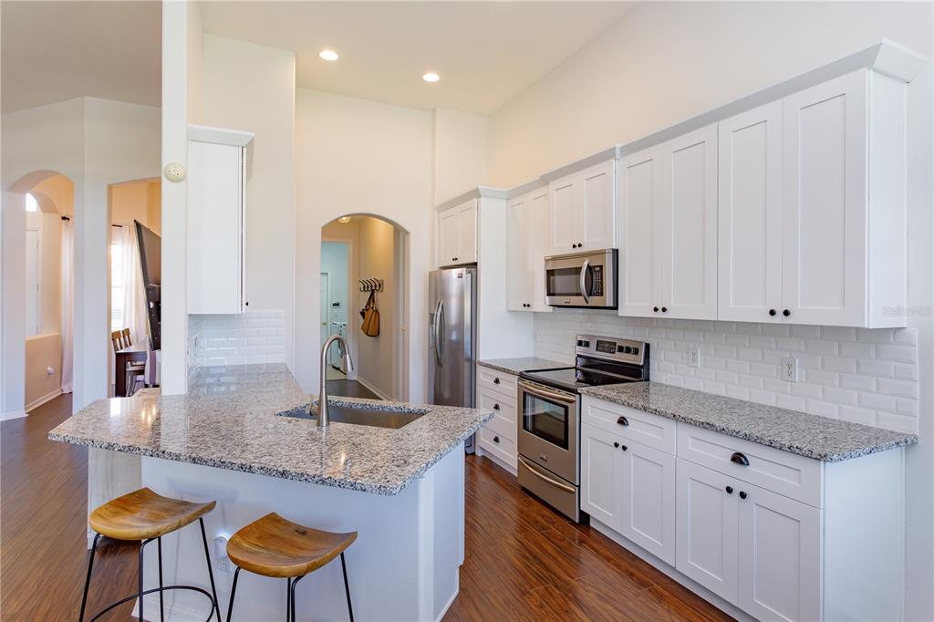 1572 St Regis Point Sanford, FL 32771 - Photo 10 of 30 a kitchen with stainless steel appliances granite countertop a stove top oven a sink dishwasher and a refrigerator with wooden floor