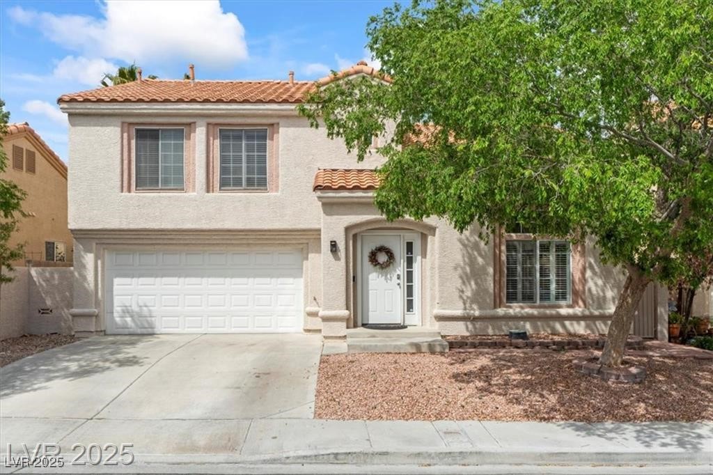 Mediterranean / spanish house with driveway, a tiled roof, stucco siding, and an attached garage