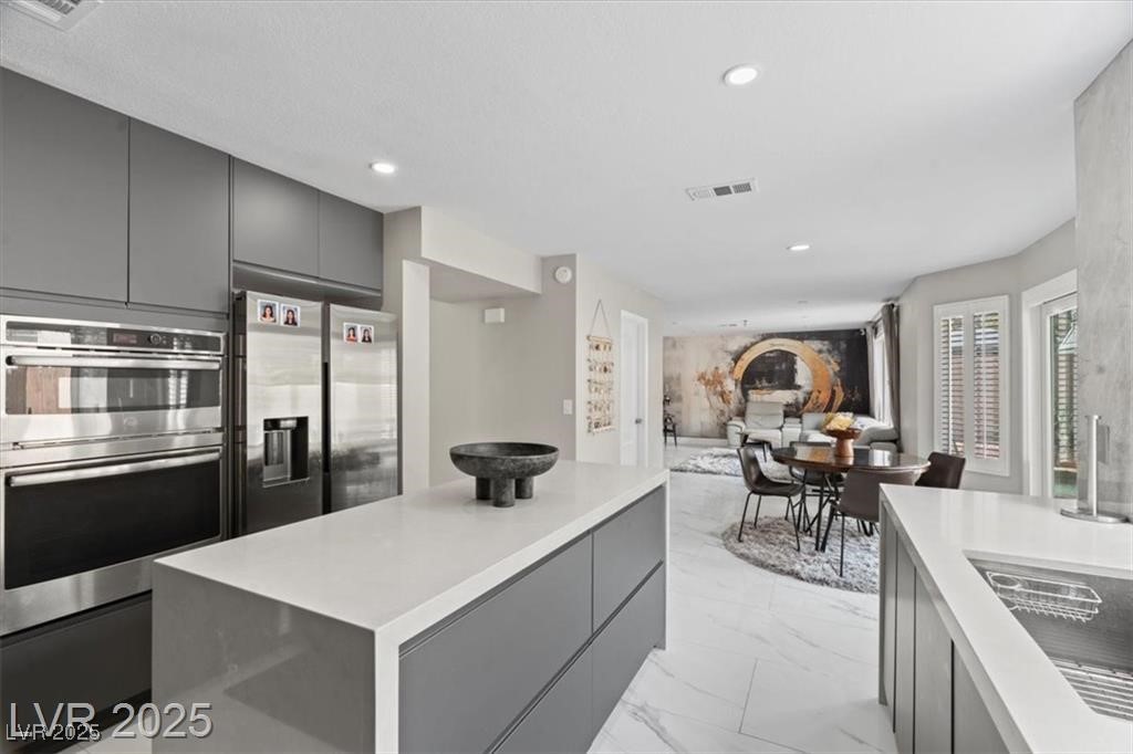 9416 Rolling Ridge Lane Las Vegas, NV 89134 - Photo 11 of 34 Kitchen featuring gray cabinets, stainless steel appliances, a center island, modern cabinets, and light marble finish floors
