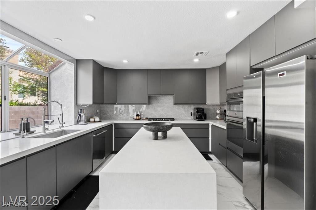 9416 Rolling Ridge Lane Las Vegas, NV 89134 - Photo 14 of 34 Kitchen featuring appliances with stainless steel finishes, modern cabinets, a center island, gray cabinetry, and light marble finish floors