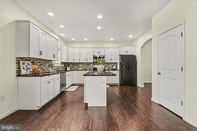 a kitchen with wooden floors white cabinets and stainless steel appliances