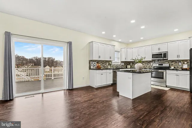 a kitchen with wooden floors white cabinets and stainless steel appliances