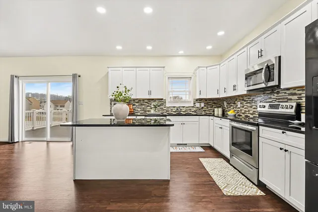a kitchen with stainless steel appliances granite countertop a stove a sink and white cabinets