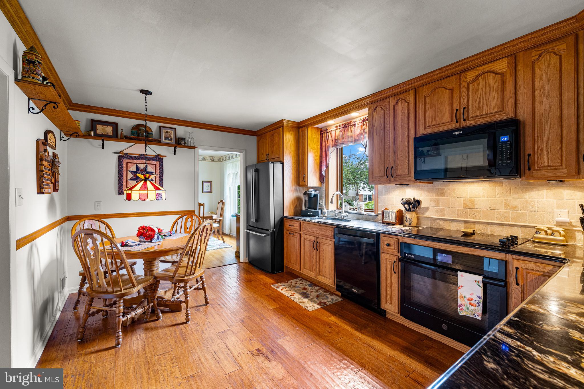 18 Whitfield Road Newark, DE 19711 - Photo 18 of 27 a kitchen with stainless steel appliances granite countertop a stove top oven a sink dishwasher a dining table and chairs with wooden floor