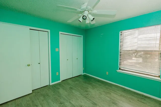 a view of an empty room with window and chandelier fan