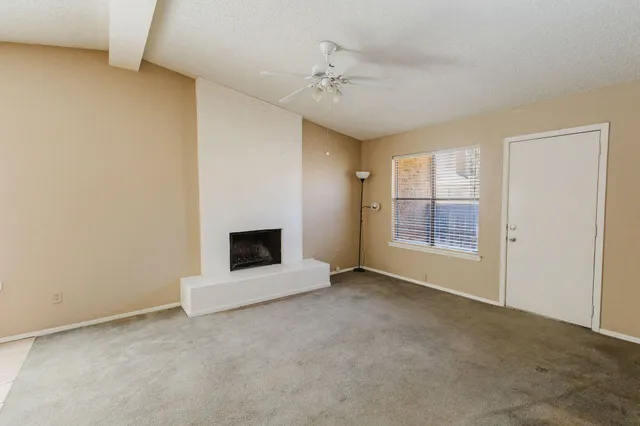 an empty room with windows and fireplace