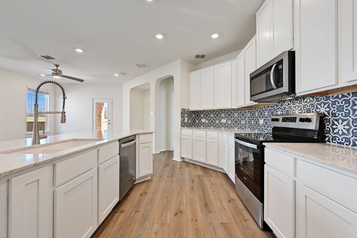 a kitchen with stainless steel appliances granite countertop a sink and microwave with wooden floors