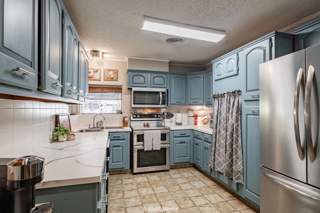 1309 Hudson Road Stamford, TX 79553 - Photo 11 of 35 a kitchen with stainless steel appliances granite countertop a refrigerator a stove top oven a sink and dishwasher