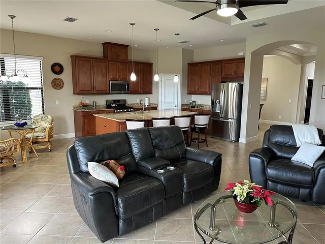 a living room with furniture kitchen view and a chandelier